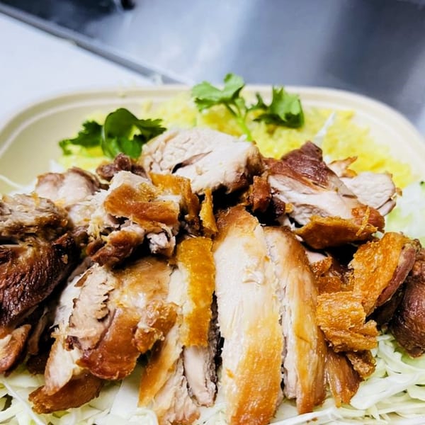 Close-up of Burd Chicken Rice, featuring crispy fried chicken pieces over shredded cabbage and yellow rice.