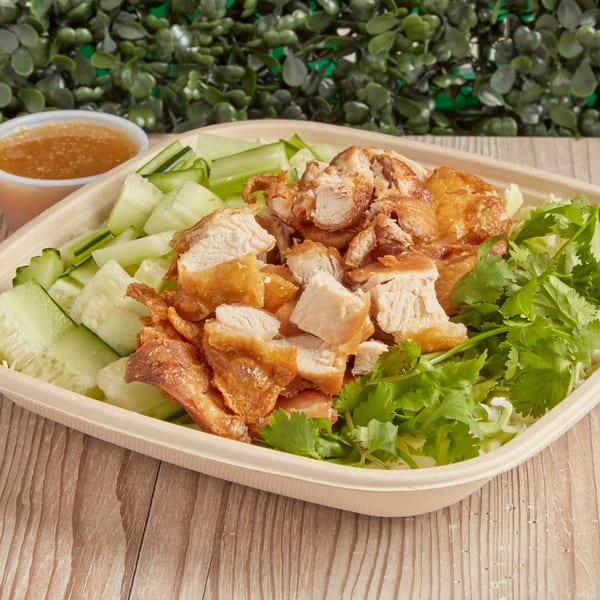 Burd Chicken Rice with crispy chicken, sliced cucumbers, cilantro, and a side of sauce.
