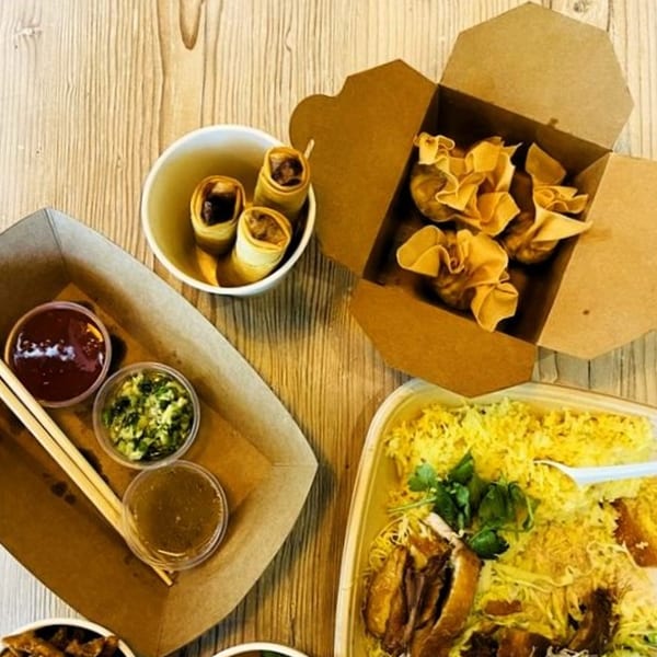 Burd Chicken Rice takeout meal with chicken rice, spring rolls, wontons, and dipping sauces.