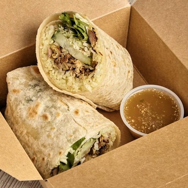 Two Burd Chicken Rice burritos with chicken, rice, and vegetables, and a side of sauce in a box.